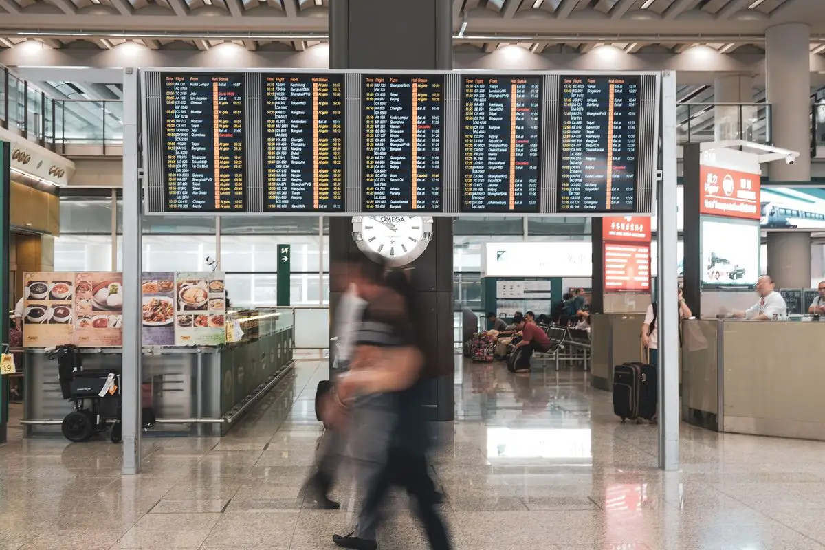 Travellers passing under airport departure boards