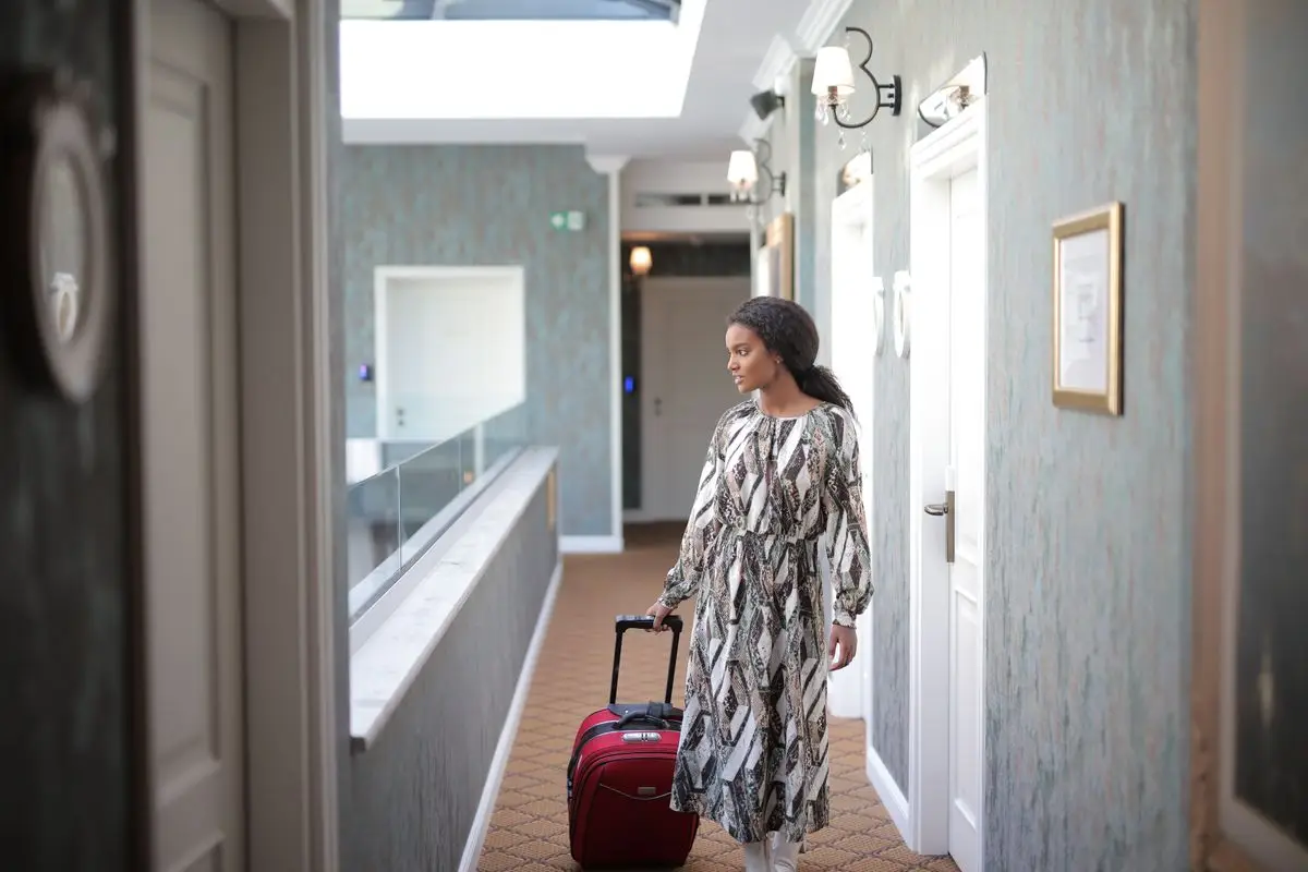 A woman with a red suitcase in a hotel corridor