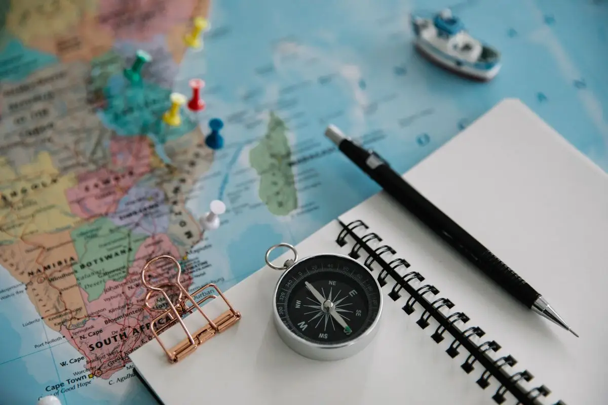 A map, notebook and compass on a table