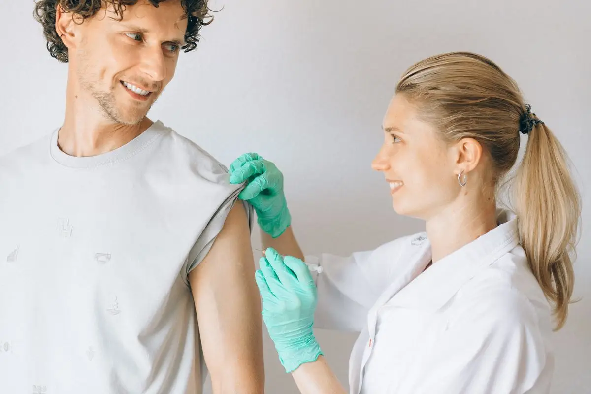 A smiling patient receiving an injection from a nurse