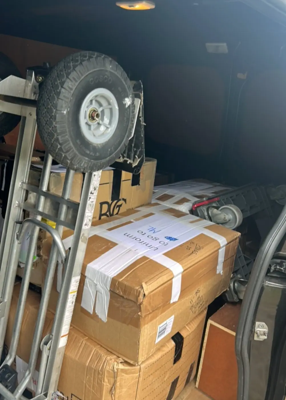 A sack truck and taped boxes in the back of a van