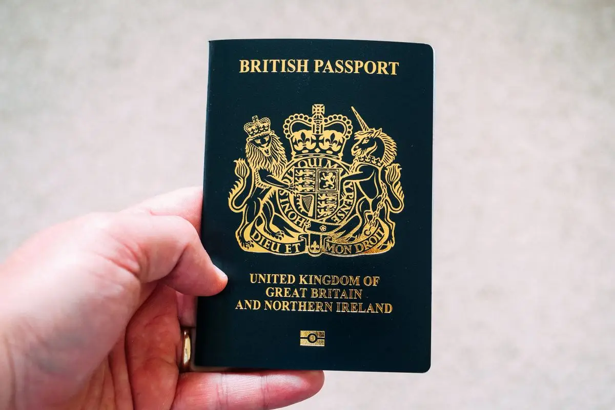 A hand holding a blue UK passport