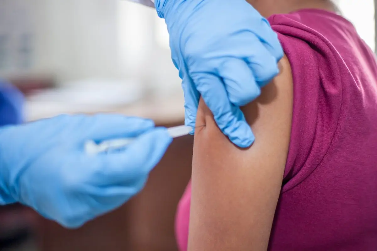 A gloved nurse giving an injection into a patient's upper arm